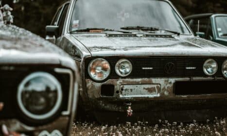 two old cars are parked in a field