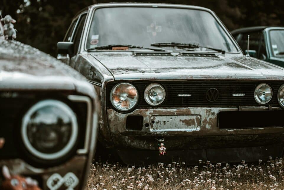 two old cars are parked in a field