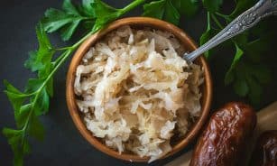 a wooden bowl filled with rice next to a spoon