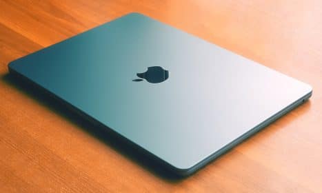an apple laptop sitting on a wooden table