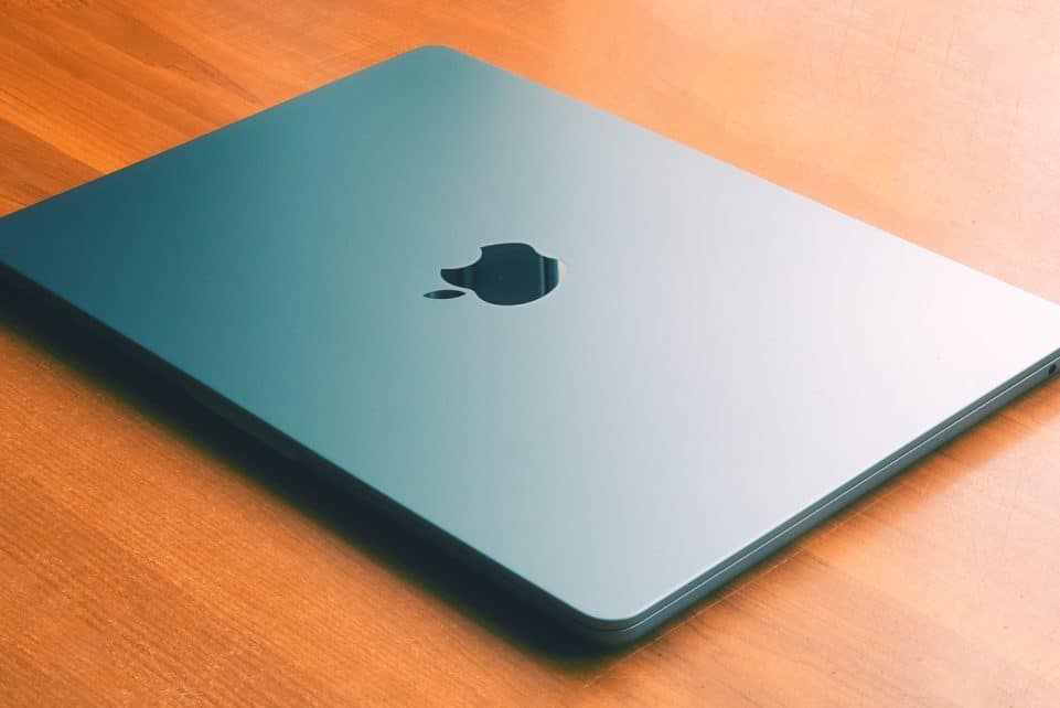 an apple laptop sitting on a wooden table