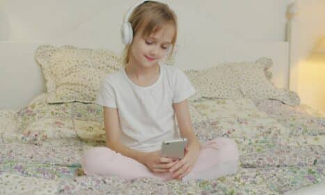 A young girl listens to music on her phone.