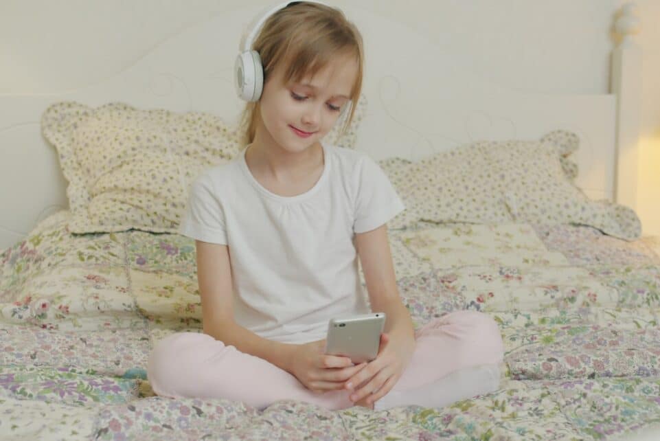A young girl listens to music on her phone.