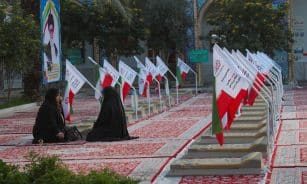 A group of people sitting on the ground in front of flags