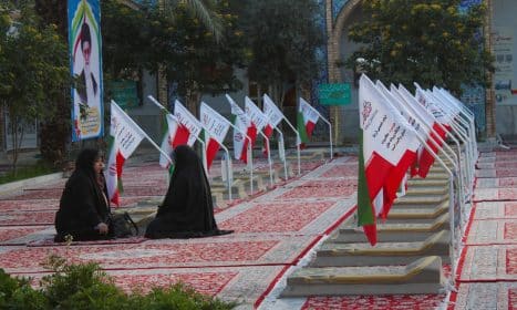 A group of people sitting on the ground in front of flags
