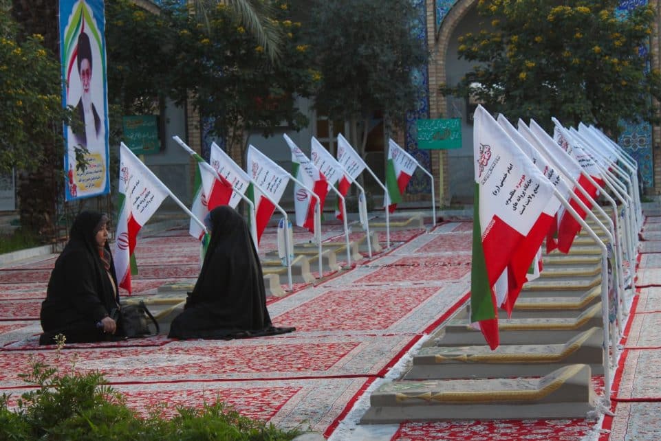A group of people sitting on the ground in front of flags