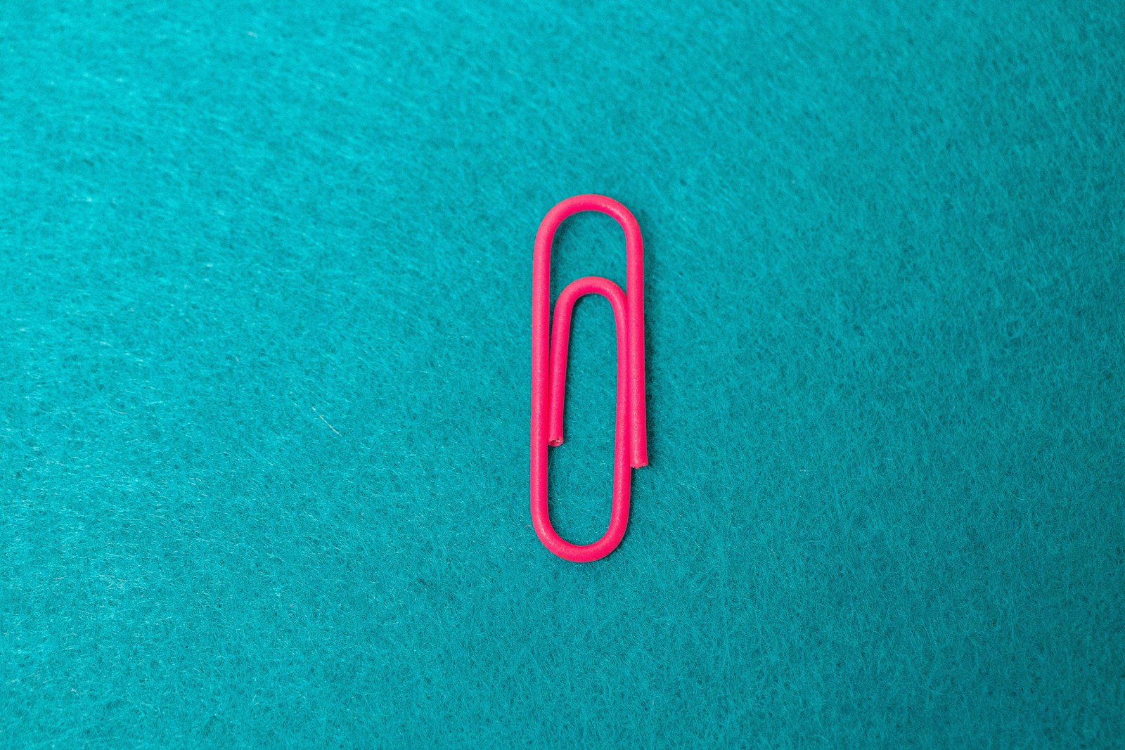 a pink paper clip sitting on top of a blue surface