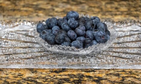 a glass bowl filled with blueberries on top of a counter