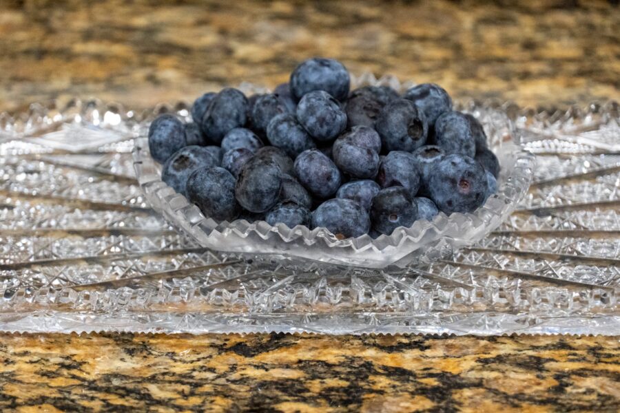 a glass bowl filled with blueberries on top of a counter