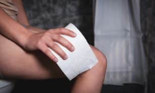 Person sitting on toilet holding toilet paper