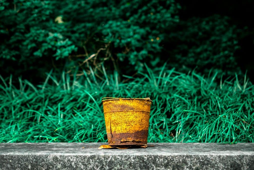 yellow and red steel bucket on gray concrete surface