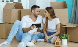Couple looking at phone surrounded by moving boxes