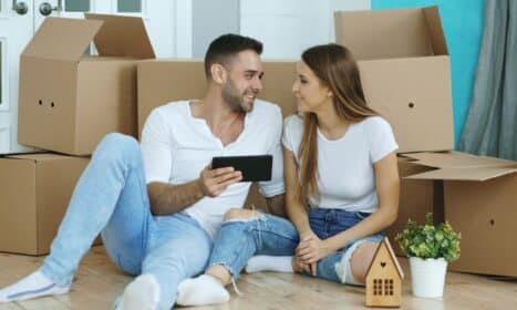 Couple looking at phone surrounded by moving boxes