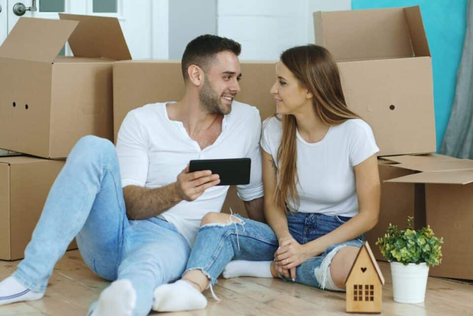 Couple looking at phone surrounded by moving boxes
