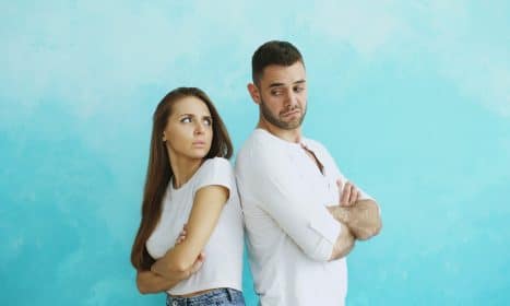 Couple standing back to back with arms crossed