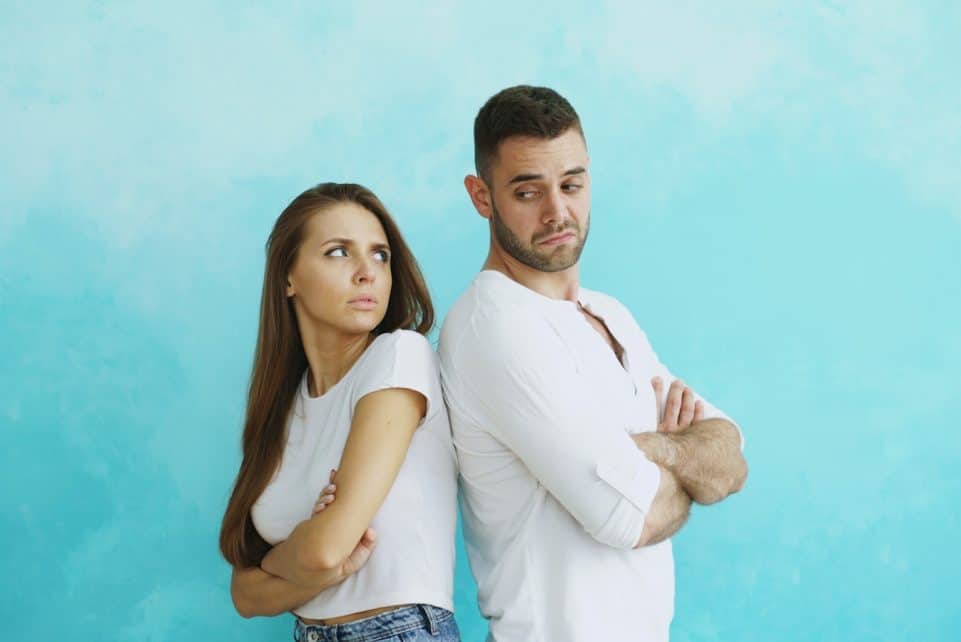 Couple standing back to back with arms crossed