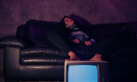 a woman sitting on a couch next to a tv
