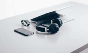 black cordless headphones beside closed black laptop computer and smartphone