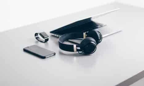 black cordless headphones beside closed black laptop computer and smartphone