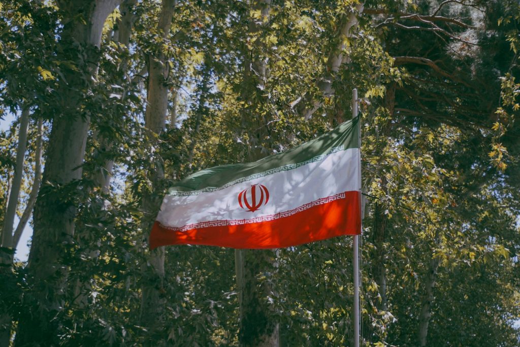 Iranian flag waving amidst green trees