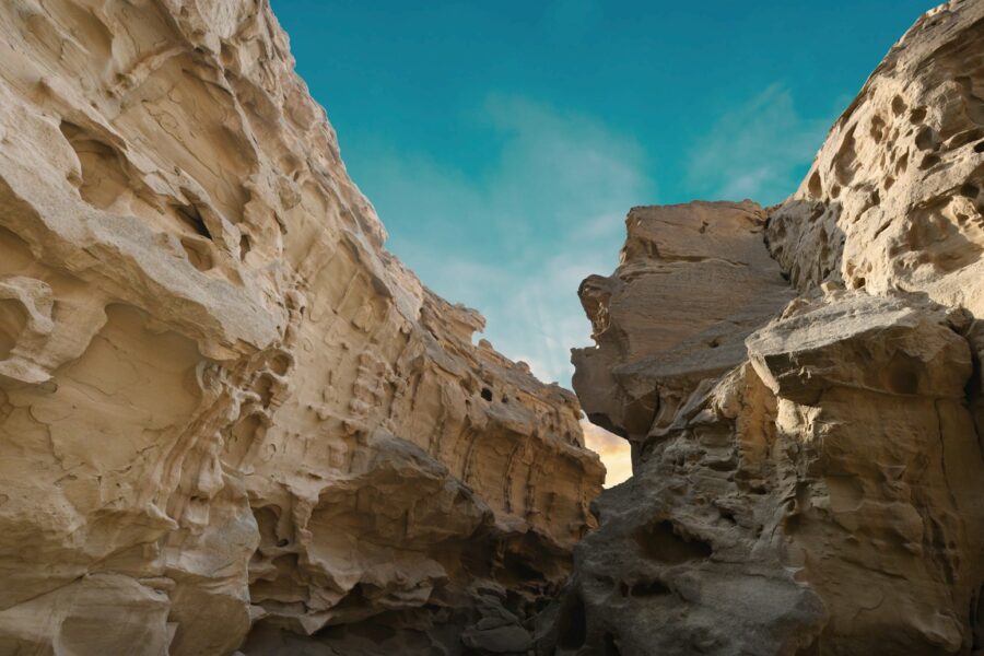 a narrow slot in a rock formation with a blue sky in the background