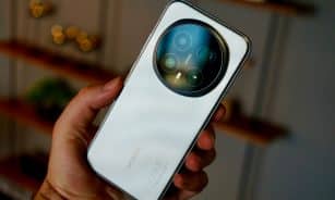 Hand holding a modern white smartphone with circular camera lens.