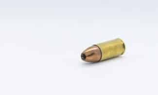 gold and silver bullet on white surface