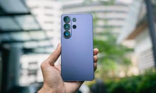 Hand holding a purple smartphone with multiple cameras.