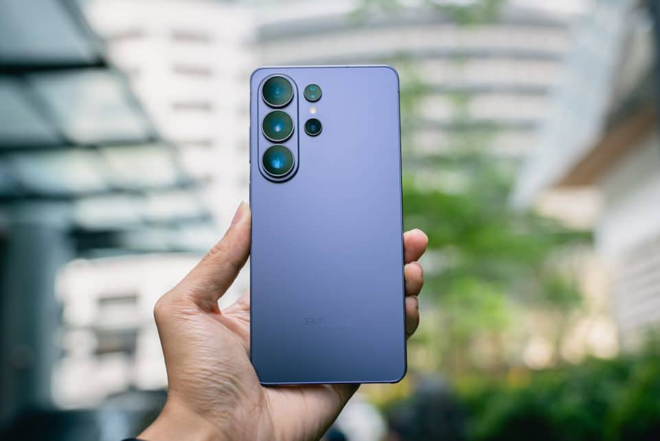 Hand holding a purple smartphone with multiple cameras.