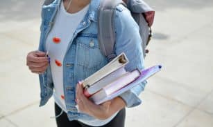 woman wearing blue denim jacket holding book