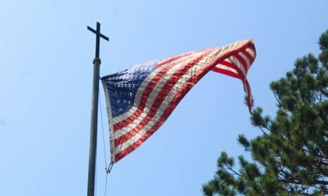 An american flag flying in the wind on a pole