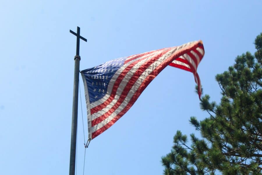 An american flag flying in the wind on a pole
