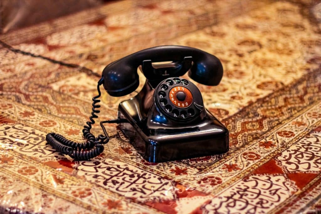 black rotary telephone on brown and white textile