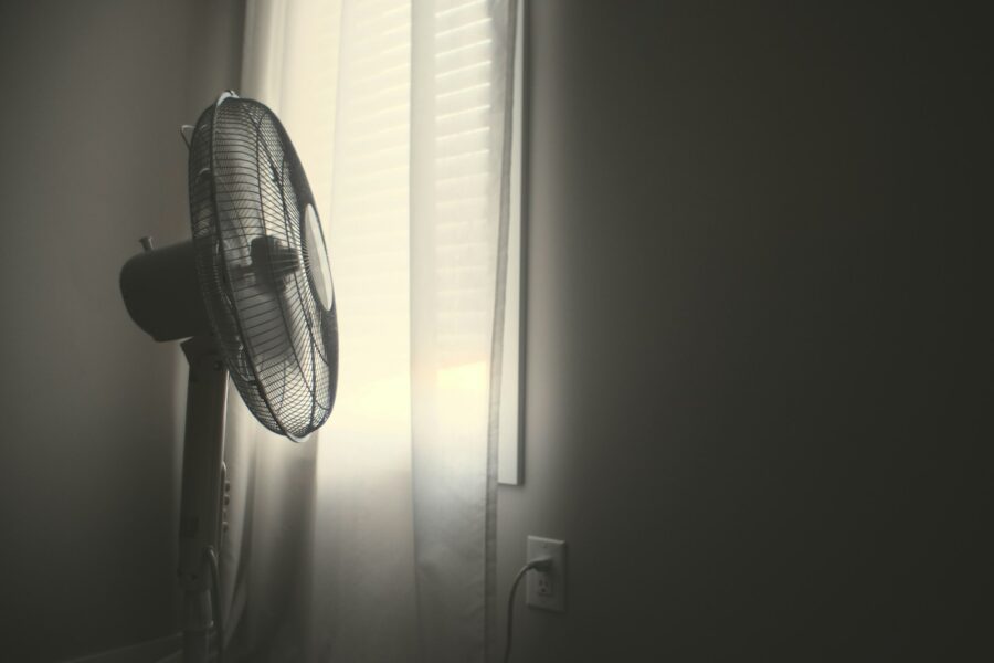 white wall fan turned on near white window blinds