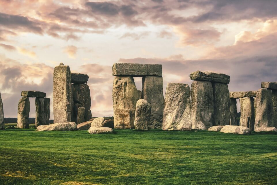 gray rock formation on green grass field under gray cloudy sky