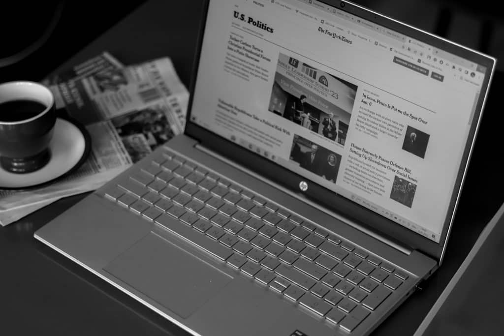 a laptop computer sitting on top of a desk next to a cup of coffee