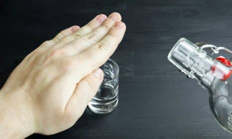 a hand reaching for a glass of water