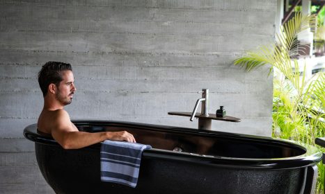 A man sitting in a black bath tub