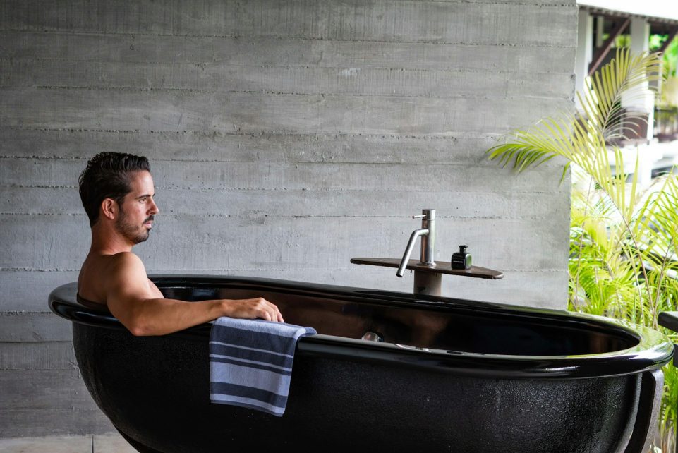 A man sitting in a black bath tub