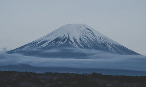 a snow covered mountain with low clouds in the foreground