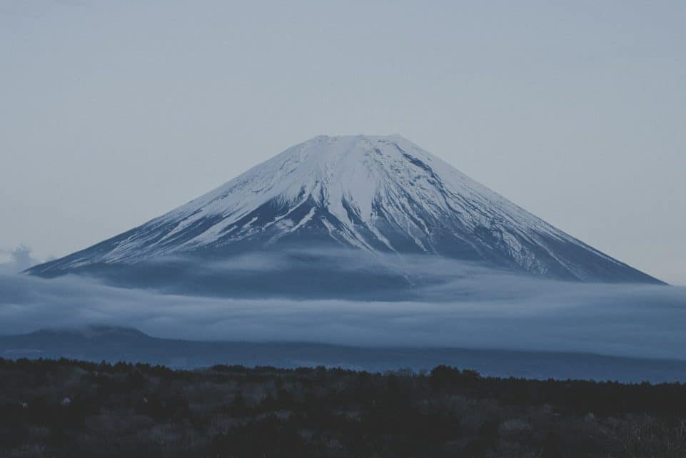 a snow covered mountain with low clouds in the foreground