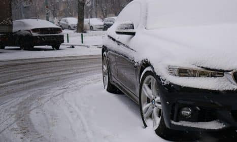 a car covered in snow on a snowy street