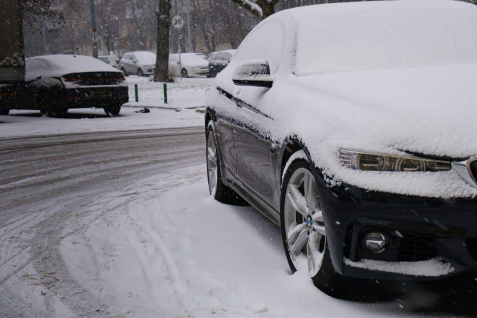 a car covered in snow on a snowy street