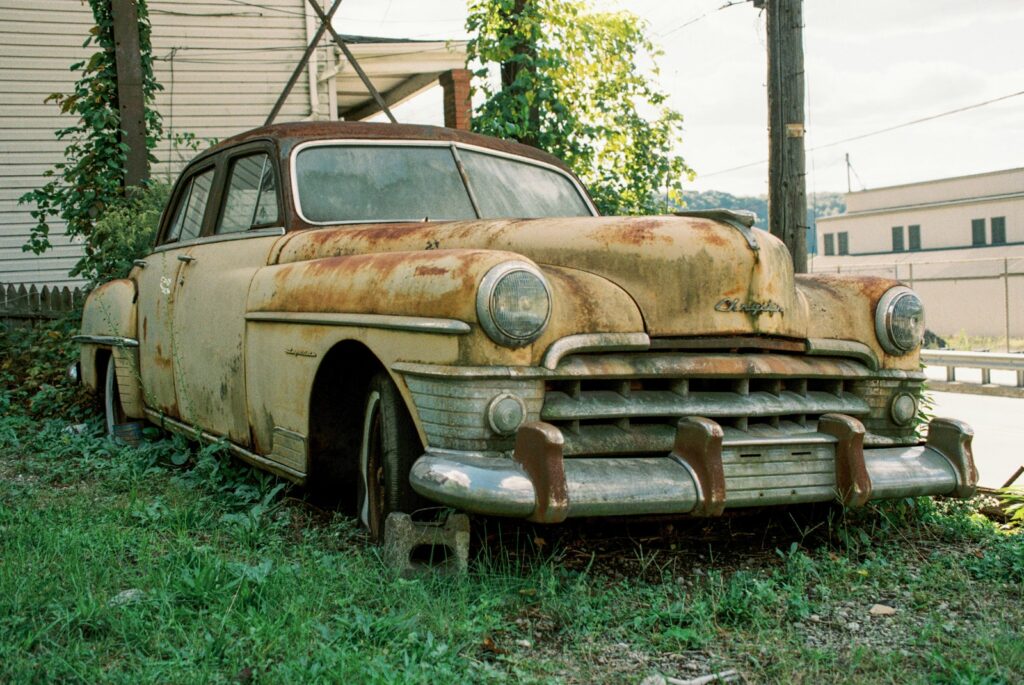 An old rusty car sitting in the grass