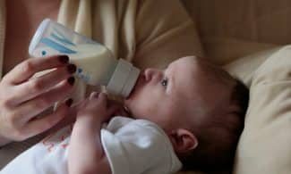 a woman feeding a baby with a bottle of milk