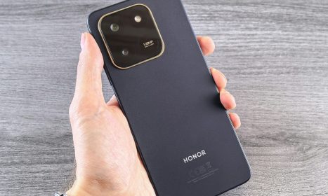 Hand holding a dark blue smartphone with camera module.