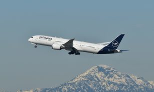 A large jetliner flying over a mountain range