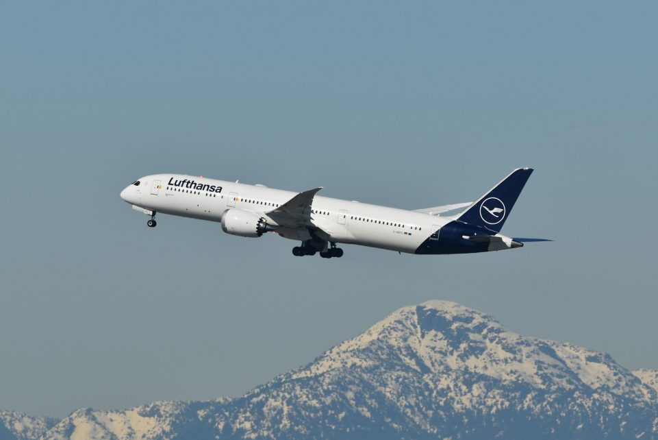 A large jetliner flying over a mountain range
