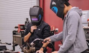 man in gray hoodie wearing blue helmet holding black and orange bicycle handle bar