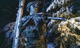 A man with a rifle standing in the snow